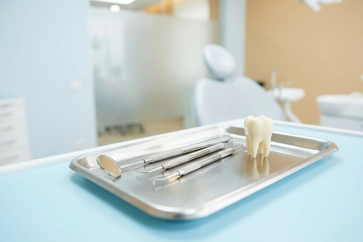 A close-up of a pristine stainless steel dental tray in a bright, modern clinic setting.